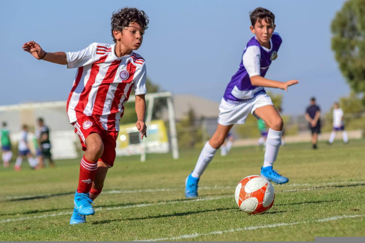 Two tween boys playing soccer game outside on field